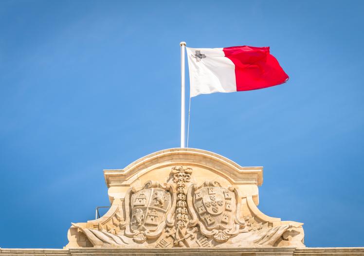 Low Angle View Of Maltese Flag On Building Against Blue Sky stock photo