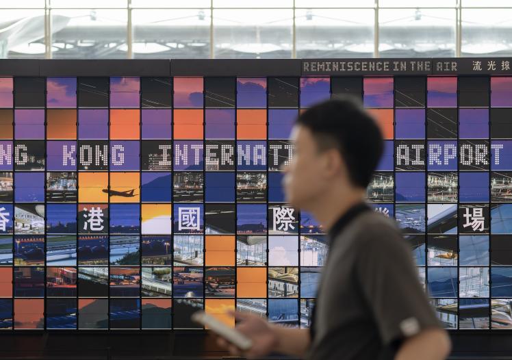Man walking past the "Reminiscence in the Air" art installation at Hong Kong Airport