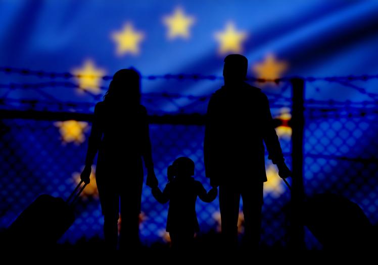 A family stands in front of a fence on the border with the European Union 