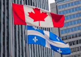 Quebec and Canada flags fluttering in the wind together in the downtown of Montreal