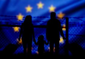 A family stands in front of a fence on the border with the European Union 