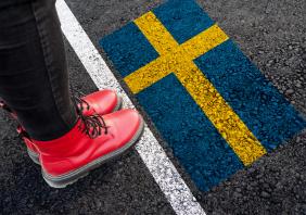 A woman with standing next to flag of Sweden