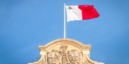 Low Angle View Of Maltese Flag On Building Against Blue Sky stock photo