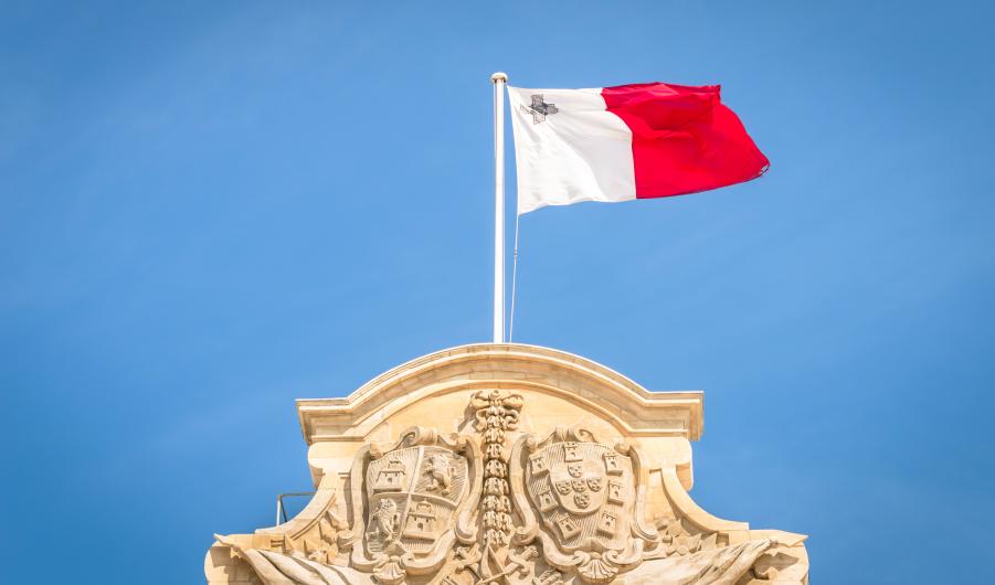 Low Angle View Of Maltese Flag On Building Against Blue Sky stock photo