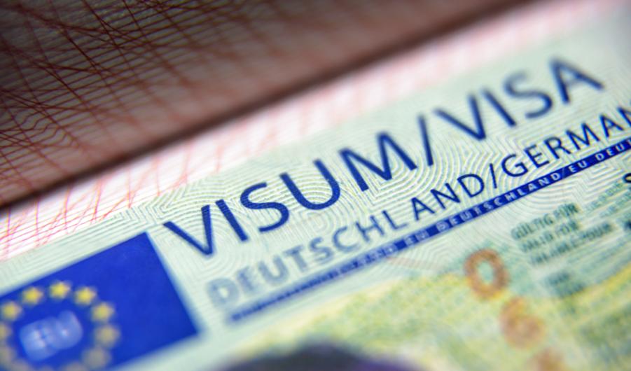 Visa stamp in passport close-up. German visitor visa at border control. Macro view of Schengen visa for tourism and travel in EU. 