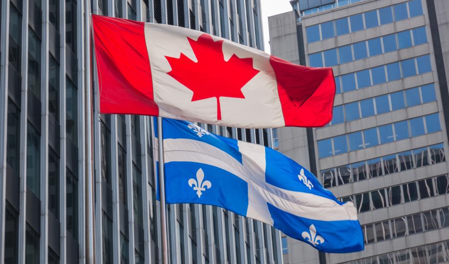 Quebec and Canada flags fluttering in the wind together in the downtown of Montreal