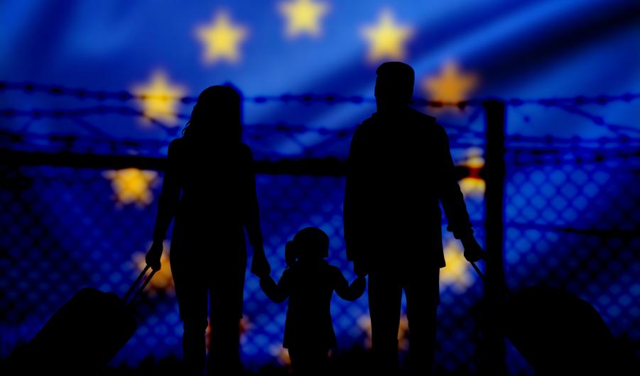 A family stands in front of a fence on the border with the European Union 