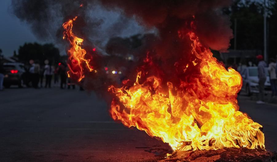Burning tyres smolder on a road during a protest action