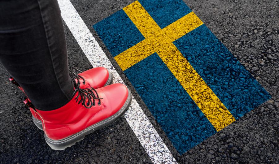 A woman with standing next to flag of Sweden